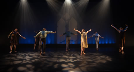 Dancers onstage with their hands wide open dance together