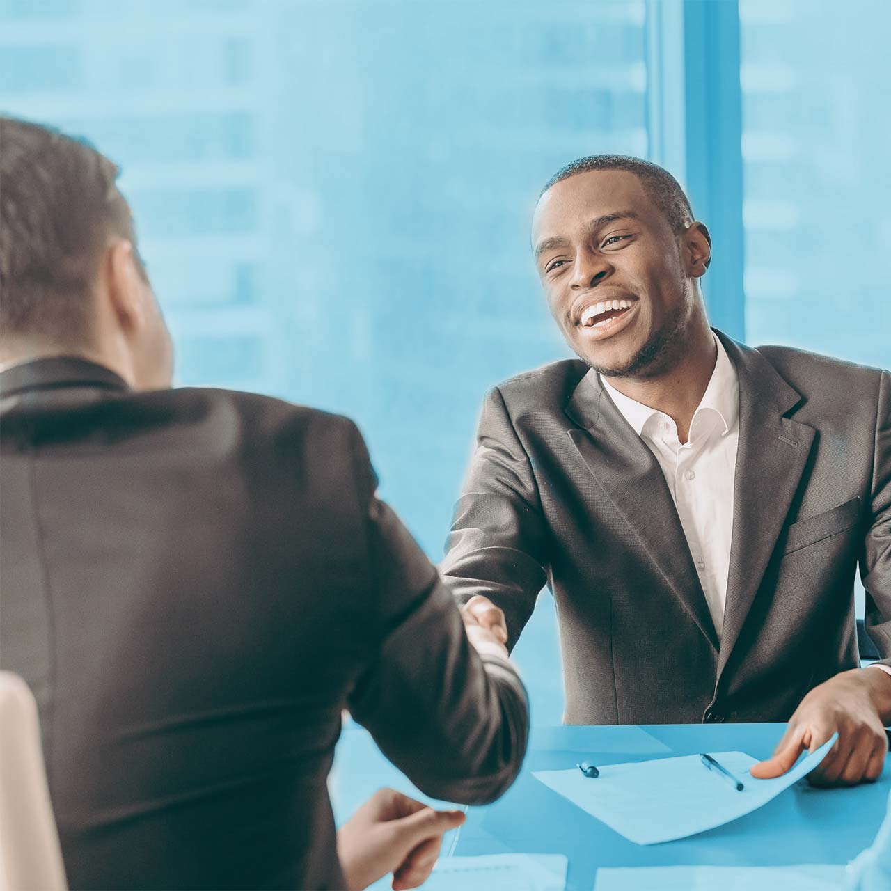 Young man smiling and handshaking another man