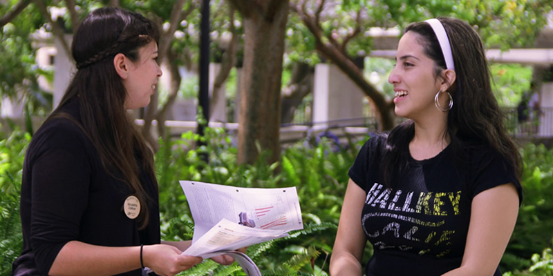 An ACCESS staff member assists a student while sitting outside