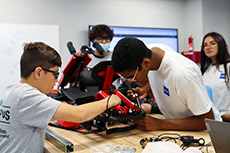 Two young students working on a device together