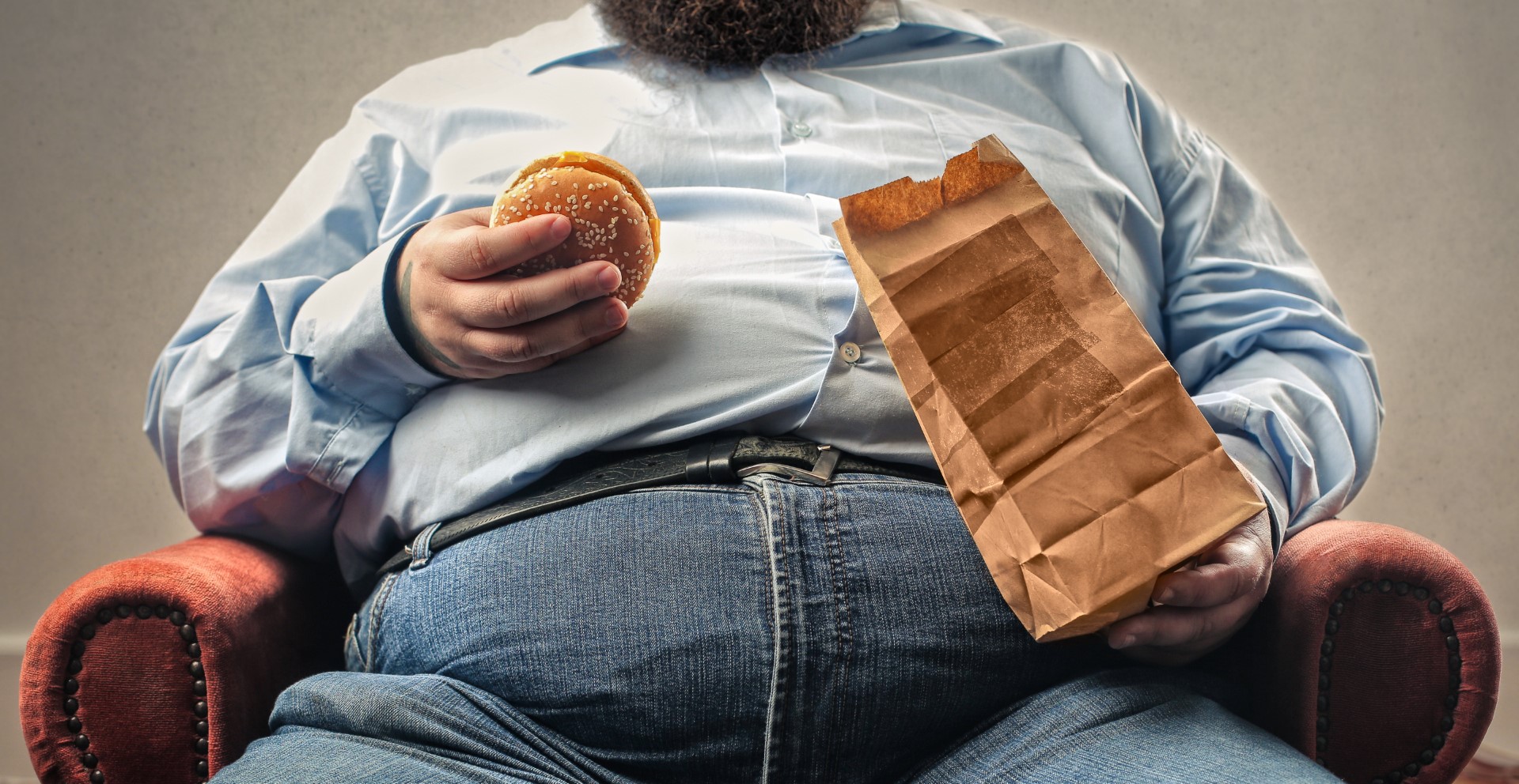 A large obese man sits in a chair