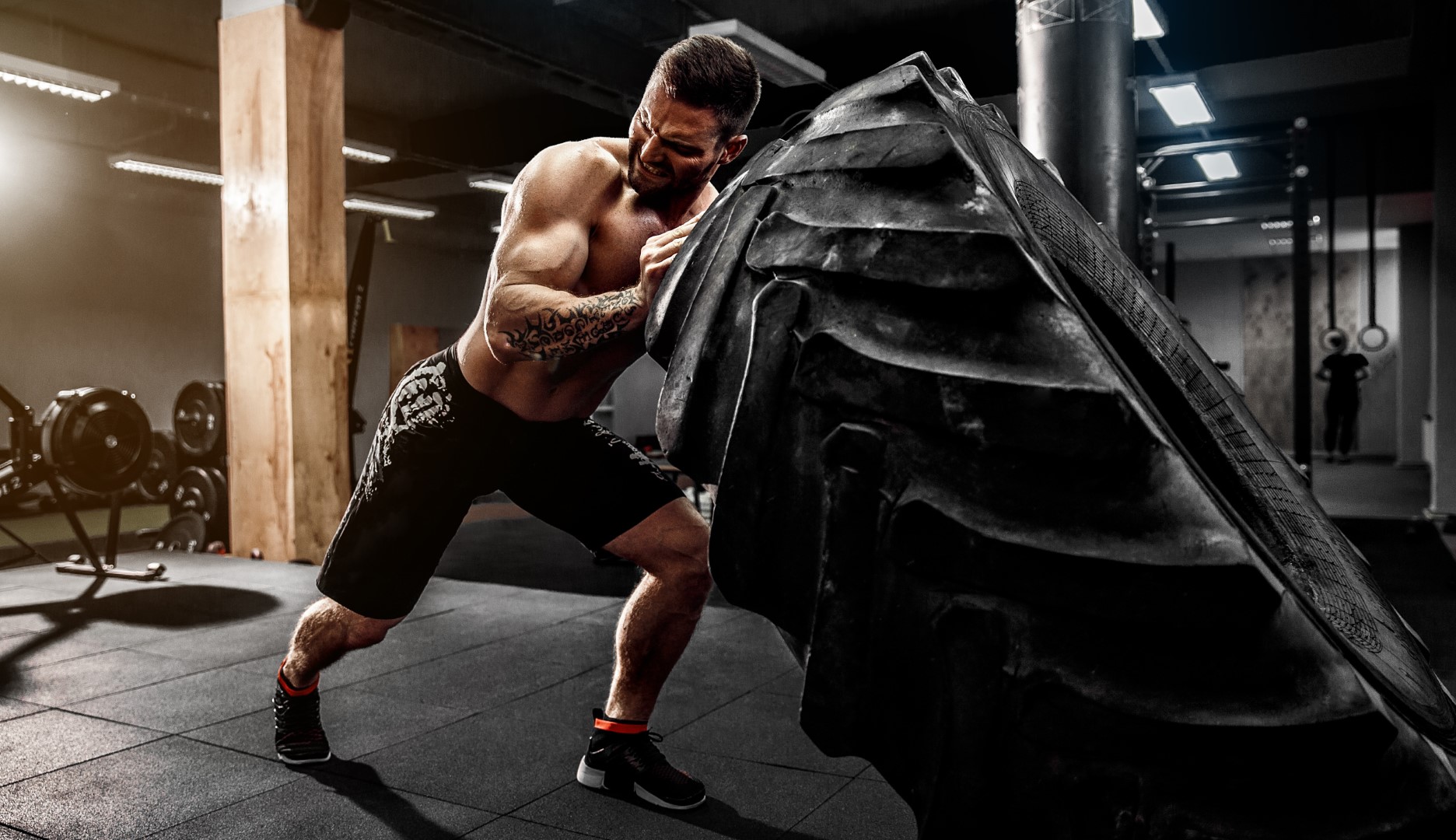 A man in a gym strenuously presses against a mahine