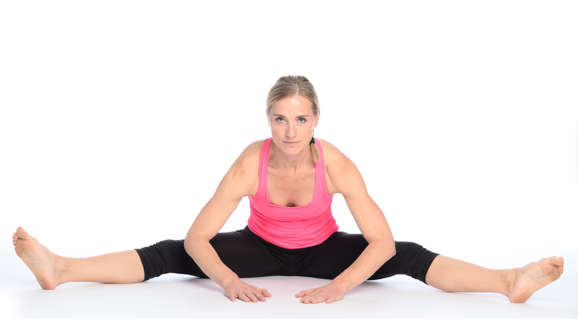 A woman demonstrates the pancake stretch on the floor