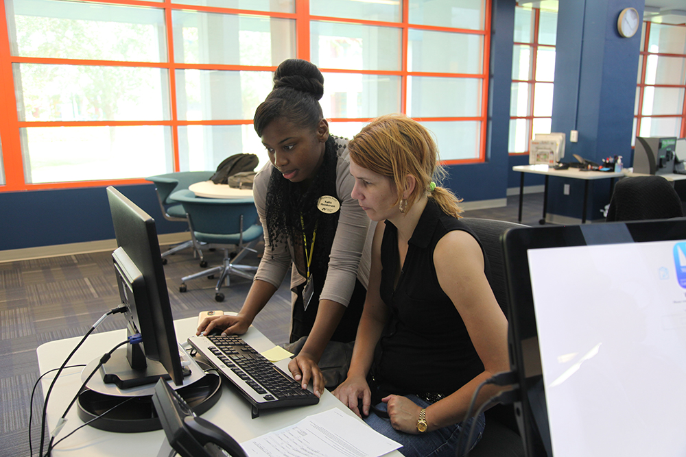 MDC faculty assisting student on a PC