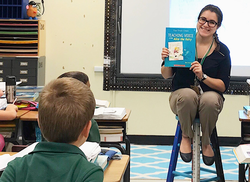 Teacher holding up a book in front of students